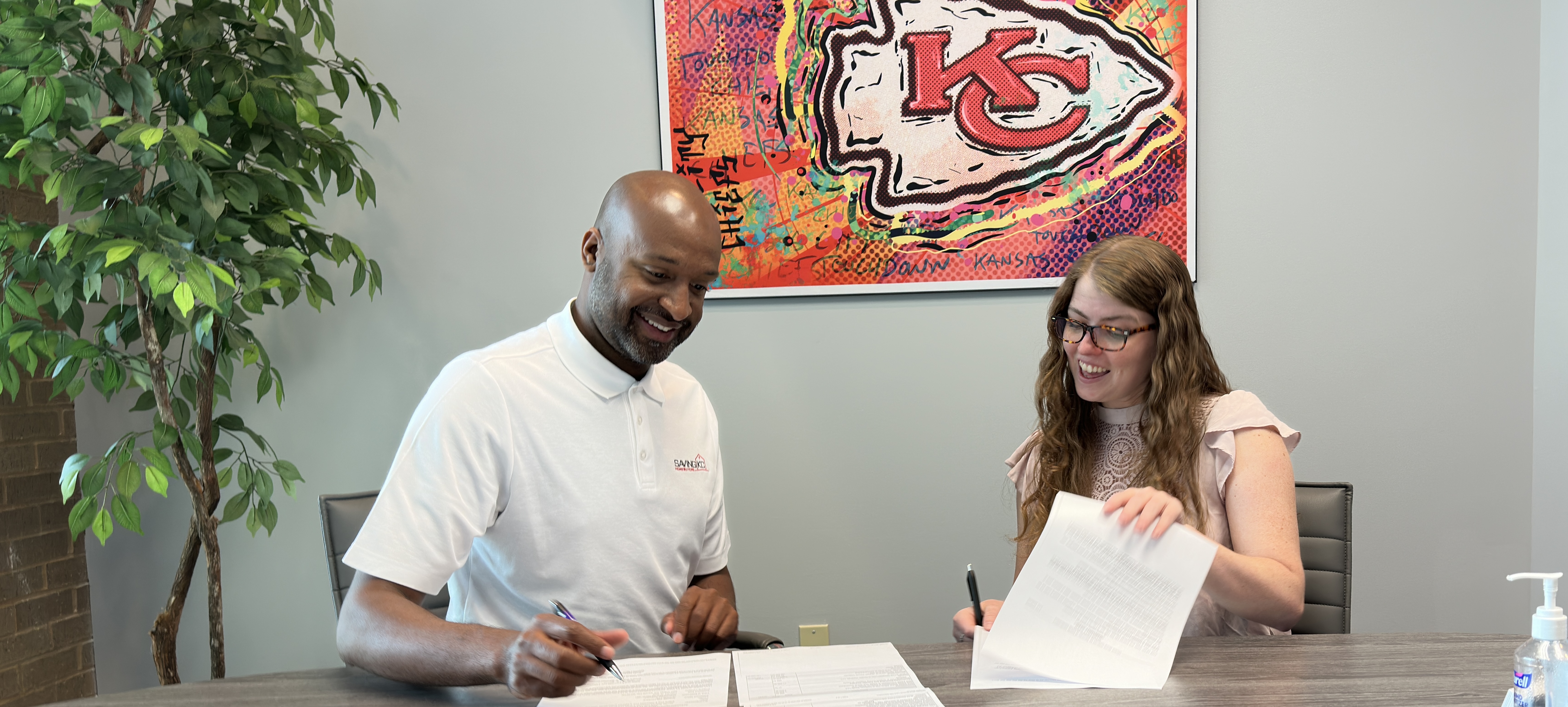 Ernest Dodson signing closing paperwork with a homeowner at Saving KC Homebuyers
